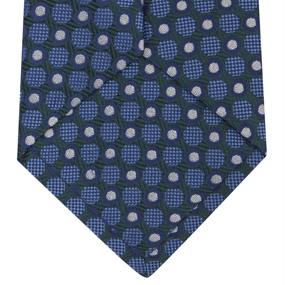 Turnbull & Asser’s Forest Green and Blue Circle and Spot Silk Tie, rolled on a white background, features a refined pattern—an elegant classic for any office shirt.
