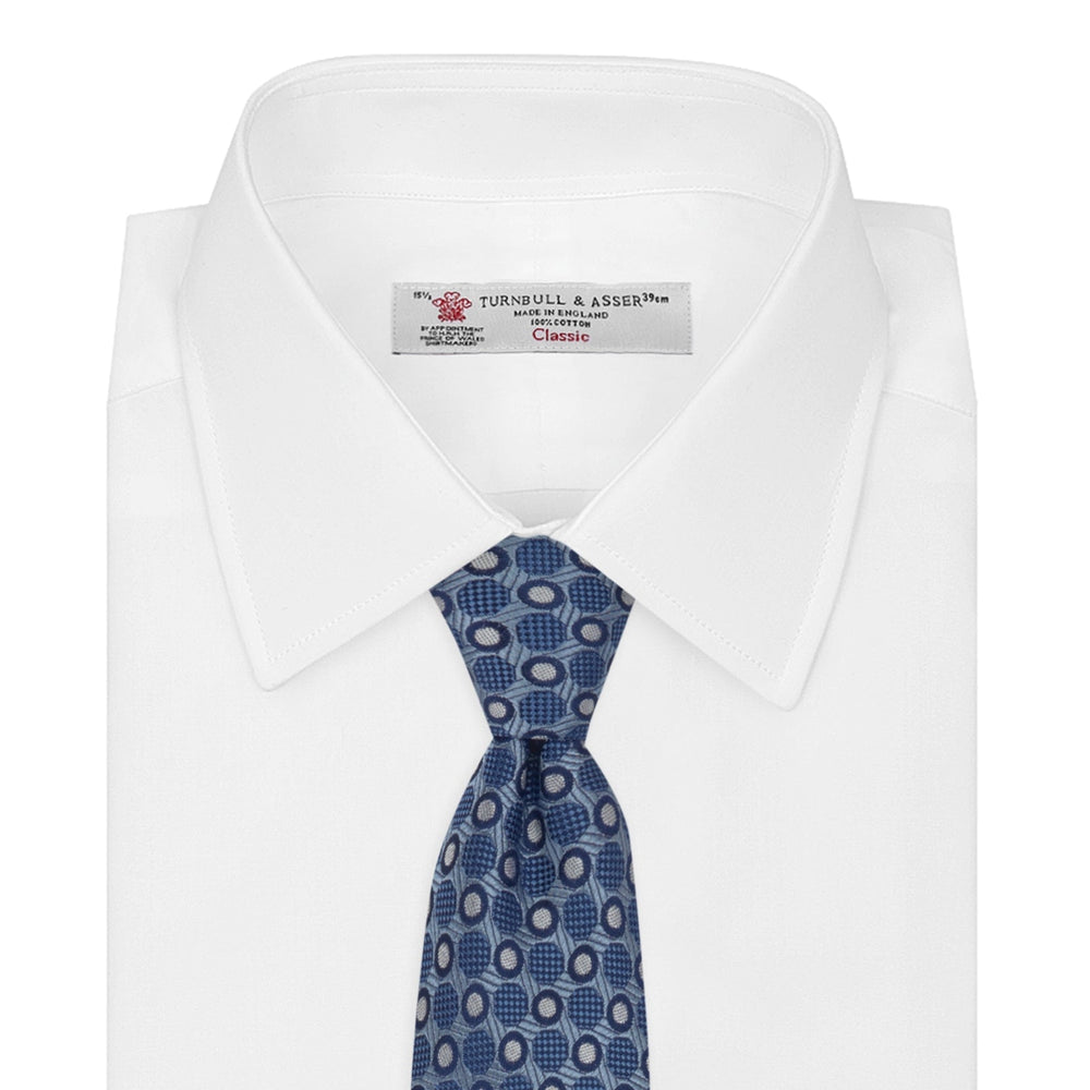 The Turnbull & Asser Blue Circle and Spot Silk Tie features a refined pattern of light blue and silver circles—ideal for pairing with an office shirt, elegantly displayed rolled on a plain white background.