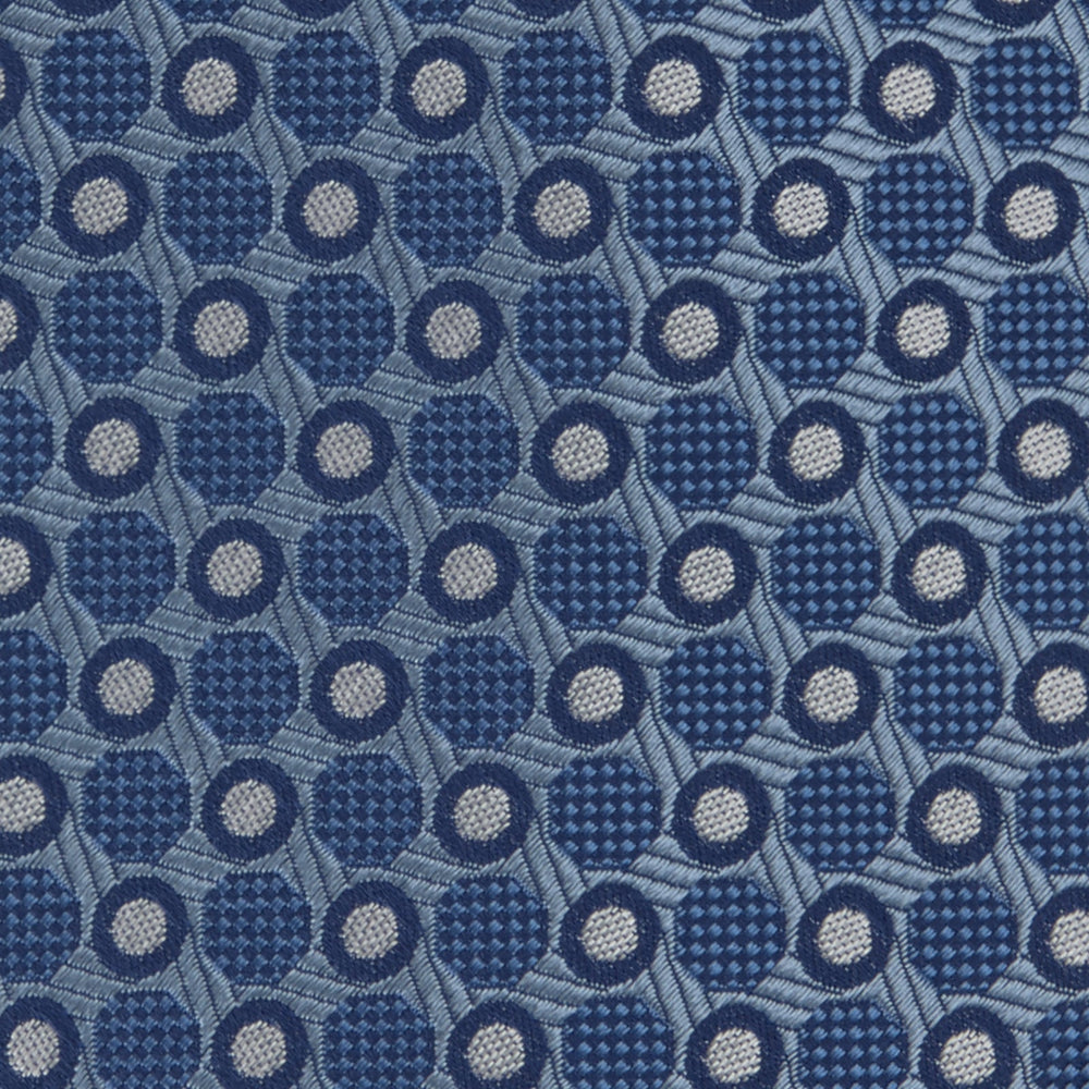 The Turnbull & Asser Blue Circle and Spot Silk Tie features a refined pattern of light blue and silver circles—ideal for pairing with an office shirt, elegantly displayed rolled on a plain white background.