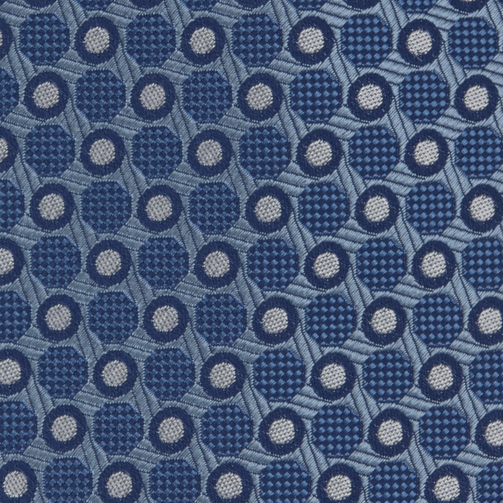 View 3 of product The Turnbull & Asser Blue Circle and Spot Silk Tie features a refined pattern of light blue and silver circles—ideal for pairing with an office shirt, elegantly displayed rolled on a plain white background.
