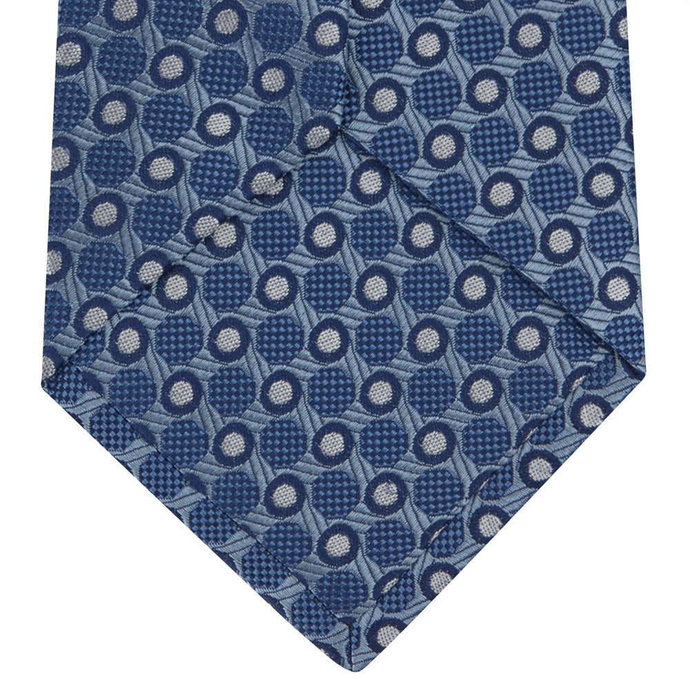 The Turnbull & Asser Blue Circle and Spot Silk Tie features a refined pattern of light blue and silver circles—ideal for pairing with an office shirt, elegantly displayed rolled on a plain white background.