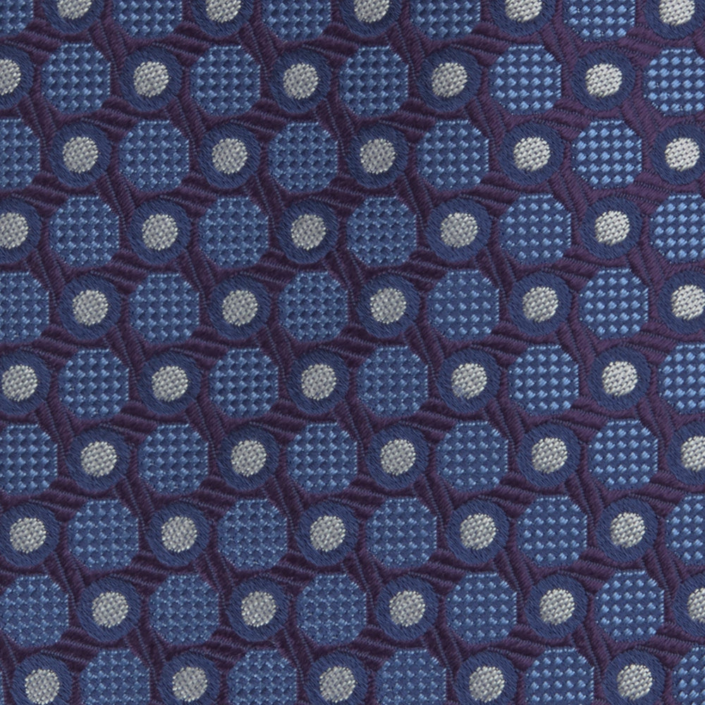 The Turnbull & Asser Plum and Blue Circle and Spot Silk Tie, shown rolled up on a white background, features a classic pattern—an elegant choice to complement any office shirt.