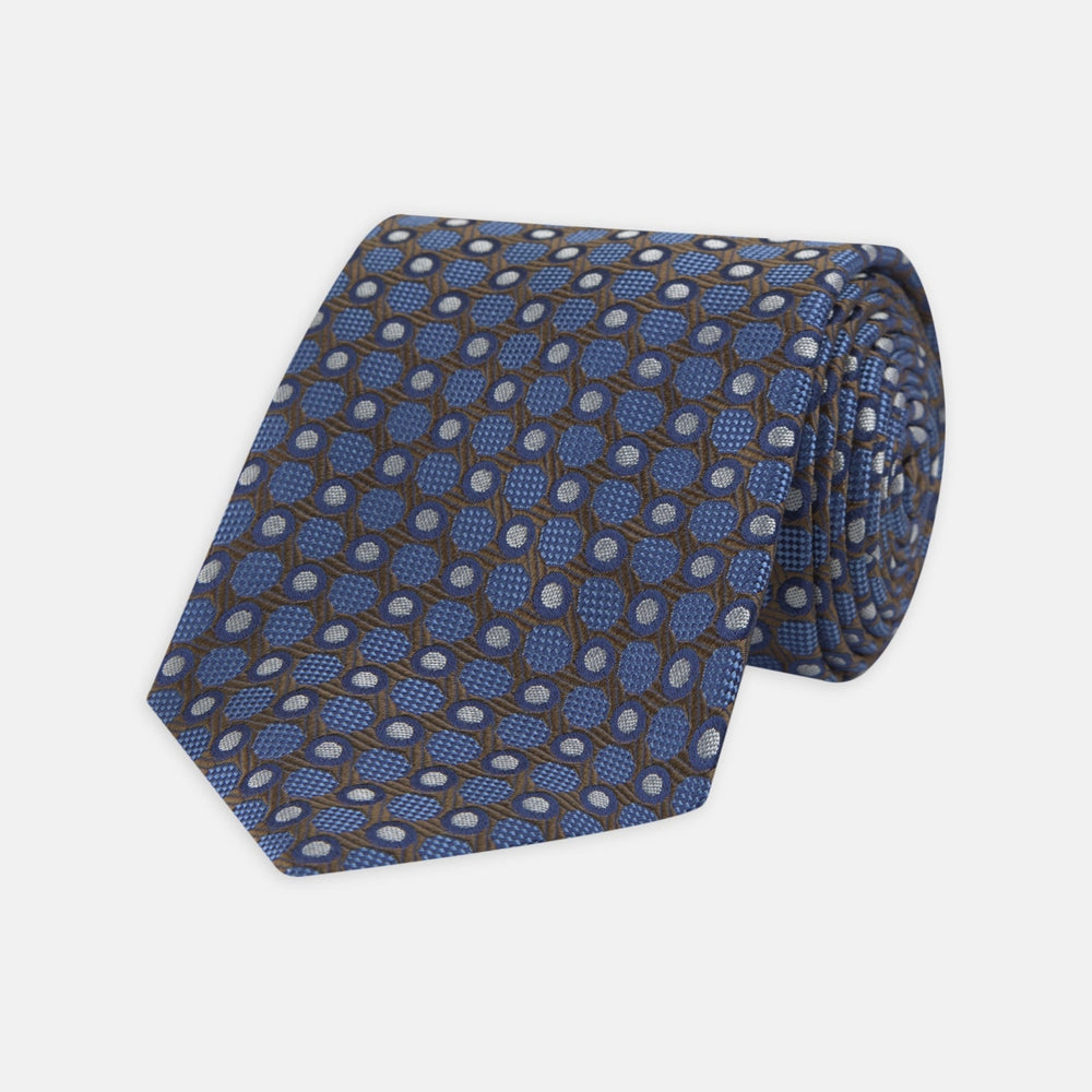 The Turnbull & Asser Brown and Blue Circle and Spot Silk Tie features a repeating pattern of brown and blue spots, ideal for office wear, shown on a white background.