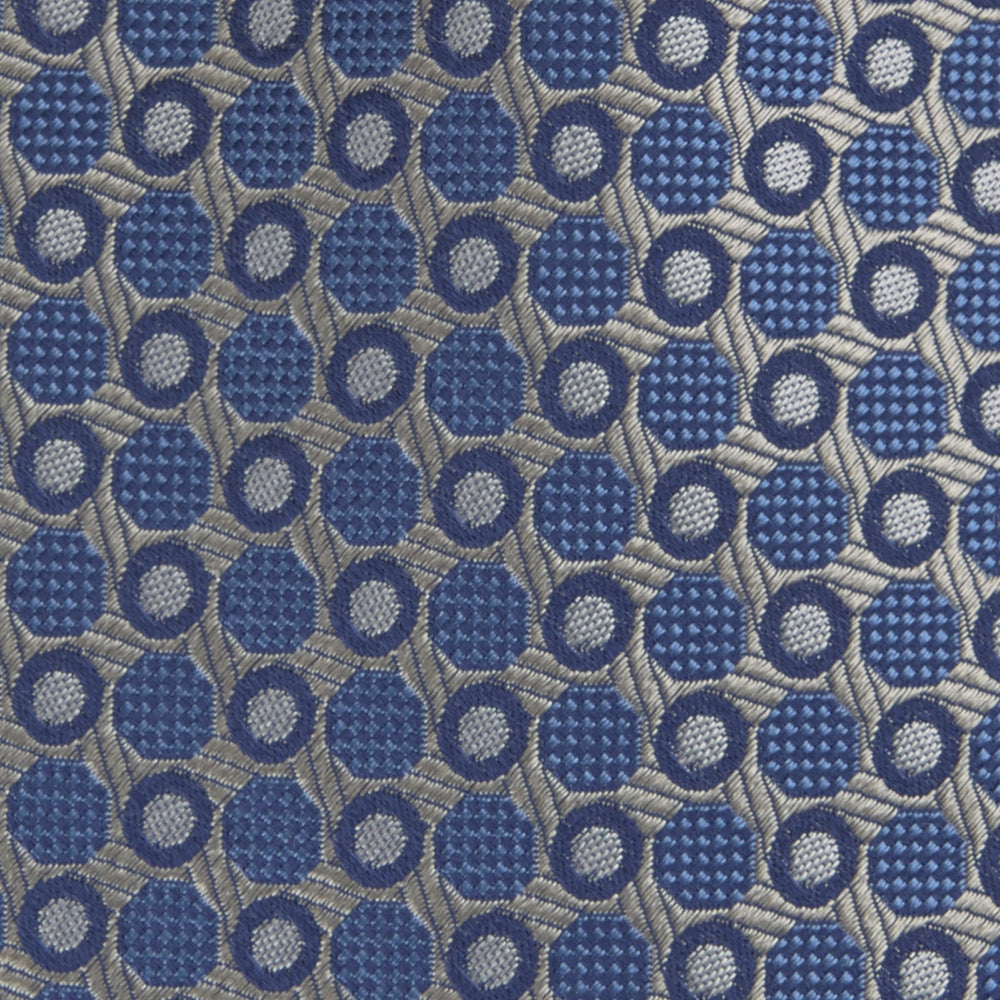 The Turnbull & Asser Silver and Blue Circle and Spot Silk Tie features a classic geometric pattern in silver and light blue on white, making it the perfect complement to any office shirt.
