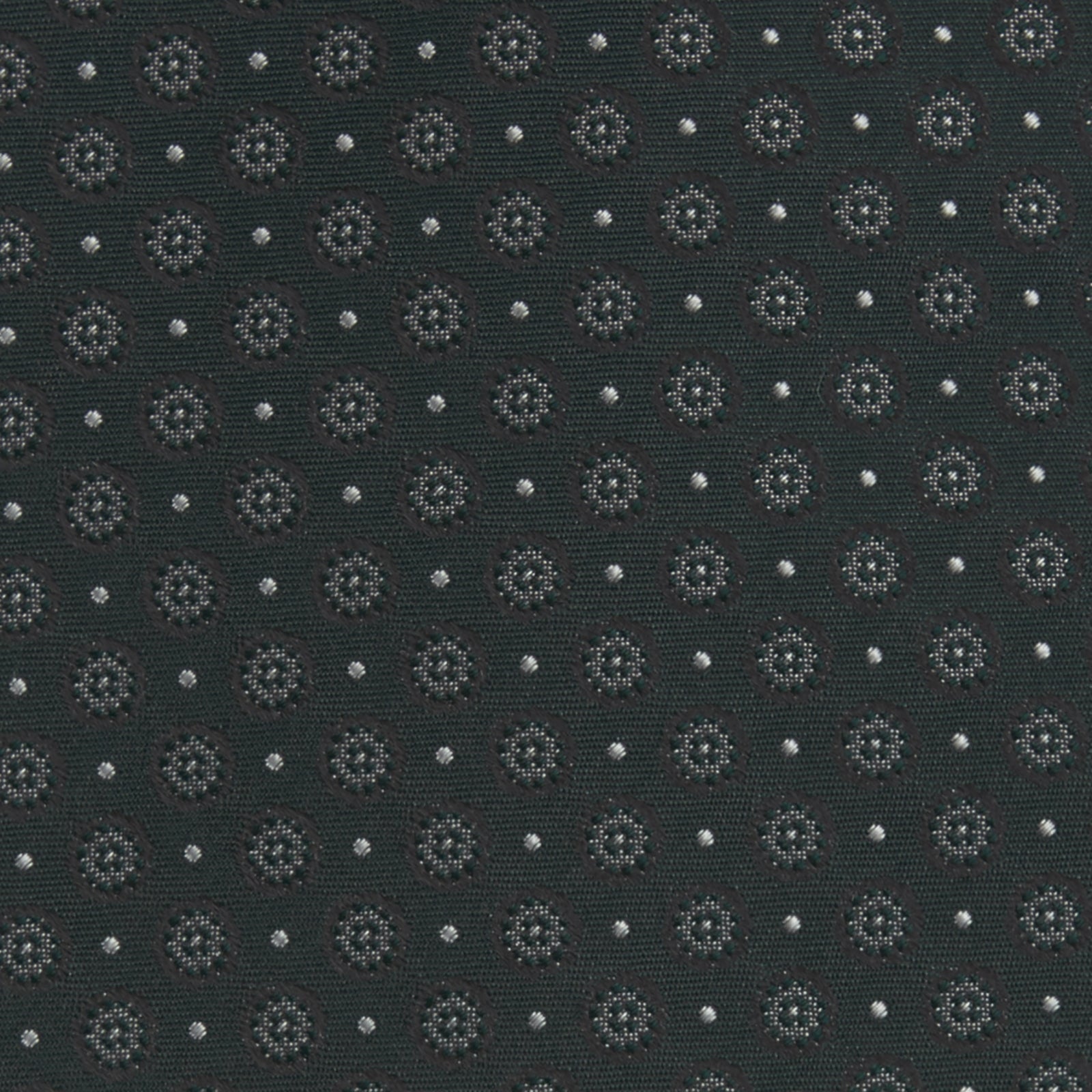 View 3 of product The Turnbull & Asser Forest Green Floral Spot Silk Tie features a subtle light gray circular pattern, shown rolled on a white background—a classic accessory ideal for office shirts.