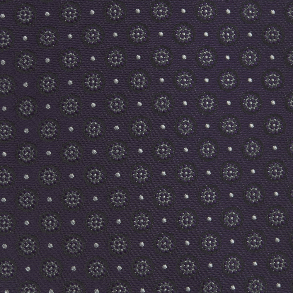 The Turnbull & Asser Plum Floral Spot Silk Tie features a rolled-up classic design with small, evenly spaced floral spots in lighter purple and white, ideal for office shirts and shown against a plain white background.