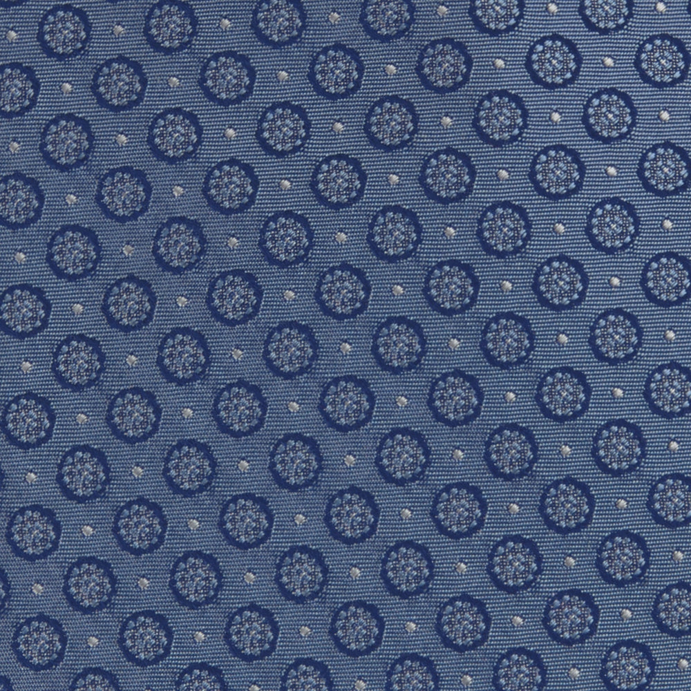 The Light Blue Floral Spot Silk Tie by Turnbull & Asser features a classic pattern in varied blue tones, rolled up on a white background—an ideal accessory to complement any office shirt.