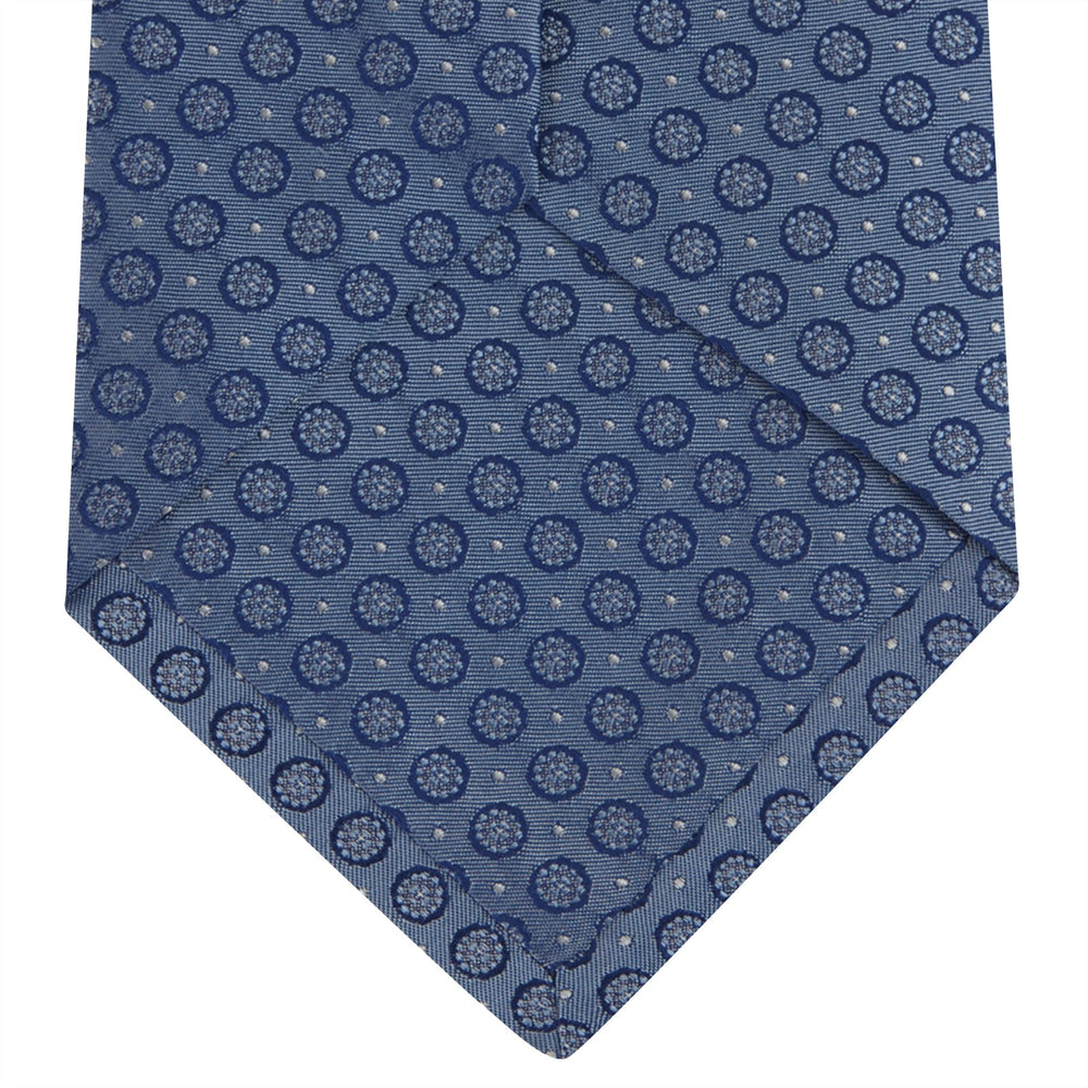 The Light Blue Floral Spot Silk Tie by Turnbull & Asser features a classic pattern in varied blue tones, rolled up on a white background—an ideal accessory to complement any office shirt.
