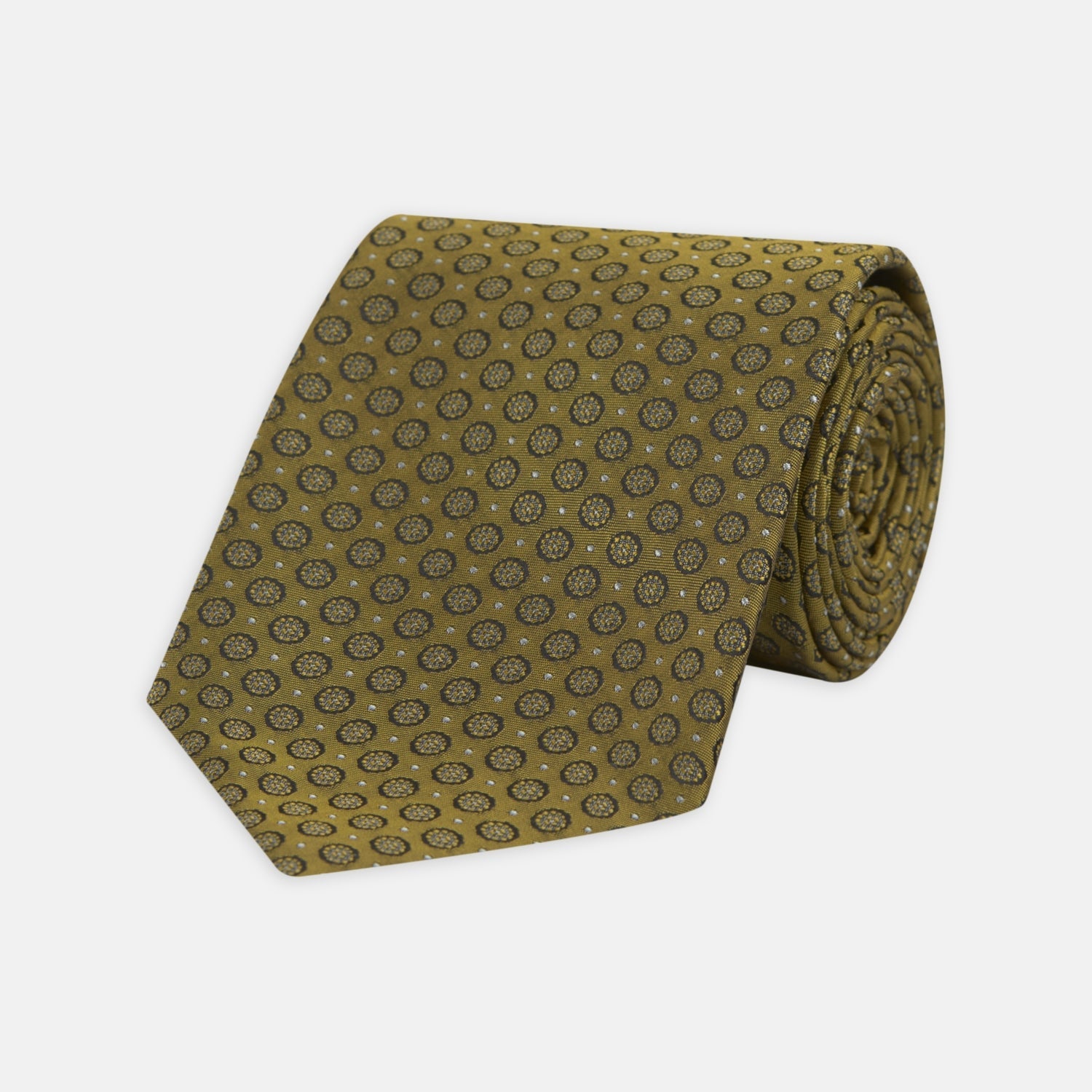 View 1 of product The Gold Floral Spot Silk Tie by Turnbull & Asser showcases a rolled-up design in olive green silk with light floral spots, perfect for adding a refined touch to any office shirt and standing out against a plain white background.