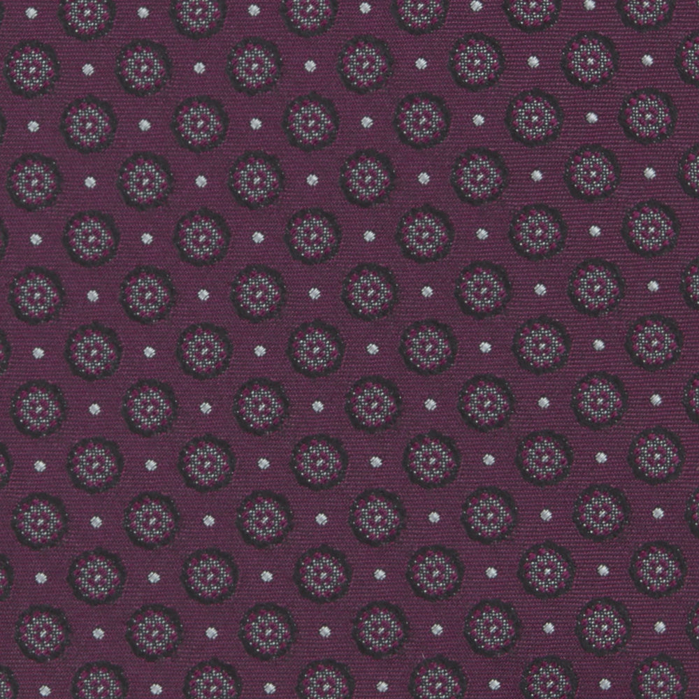 The Turnbull & Asser Wine Floral Spot Silk Tie features a rolled design with a gray and black circular pattern, perfect for the office. Displayed on a plain white background.