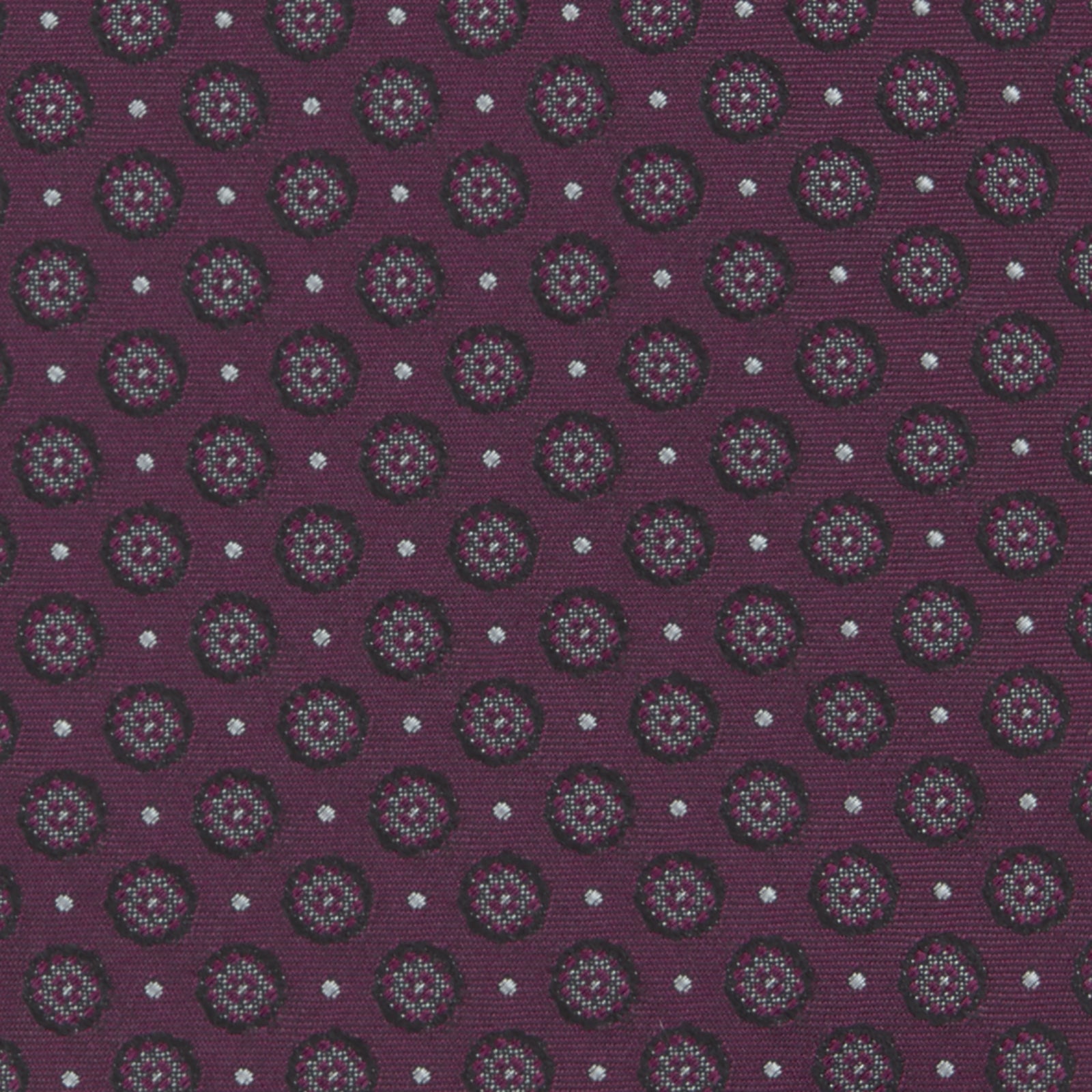 View 3 of product The Turnbull & Asser Wine Floral Spot Silk Tie features a rolled design with a gray and black circular pattern, perfect for the office. Displayed on a plain white background.