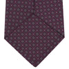 View 4 of product The Turnbull & Asser Wine Floral Spot Silk Tie features a rolled design with a gray and black circular pattern, perfect for the office. Displayed on a plain white background.