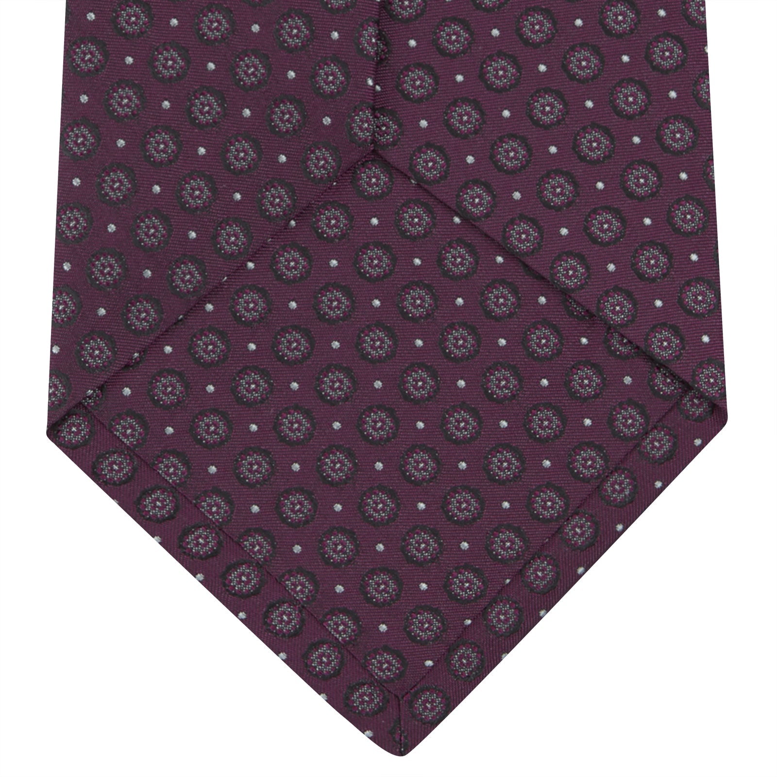 View 4 of product The Turnbull & Asser Wine Floral Spot Silk Tie features a rolled design with a gray and black circular pattern, perfect for the office. Displayed on a plain white background.
