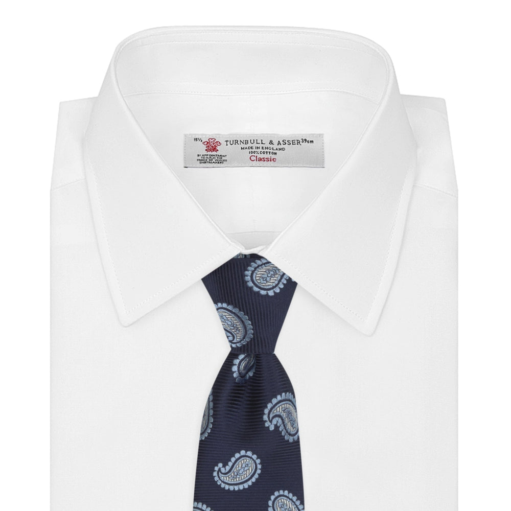 The Turnbull & Asser Navy and Light Blue Floating Paisley Silk Tie features a repeating light blue and white paisley pattern set against a navy blue silk backdrop.