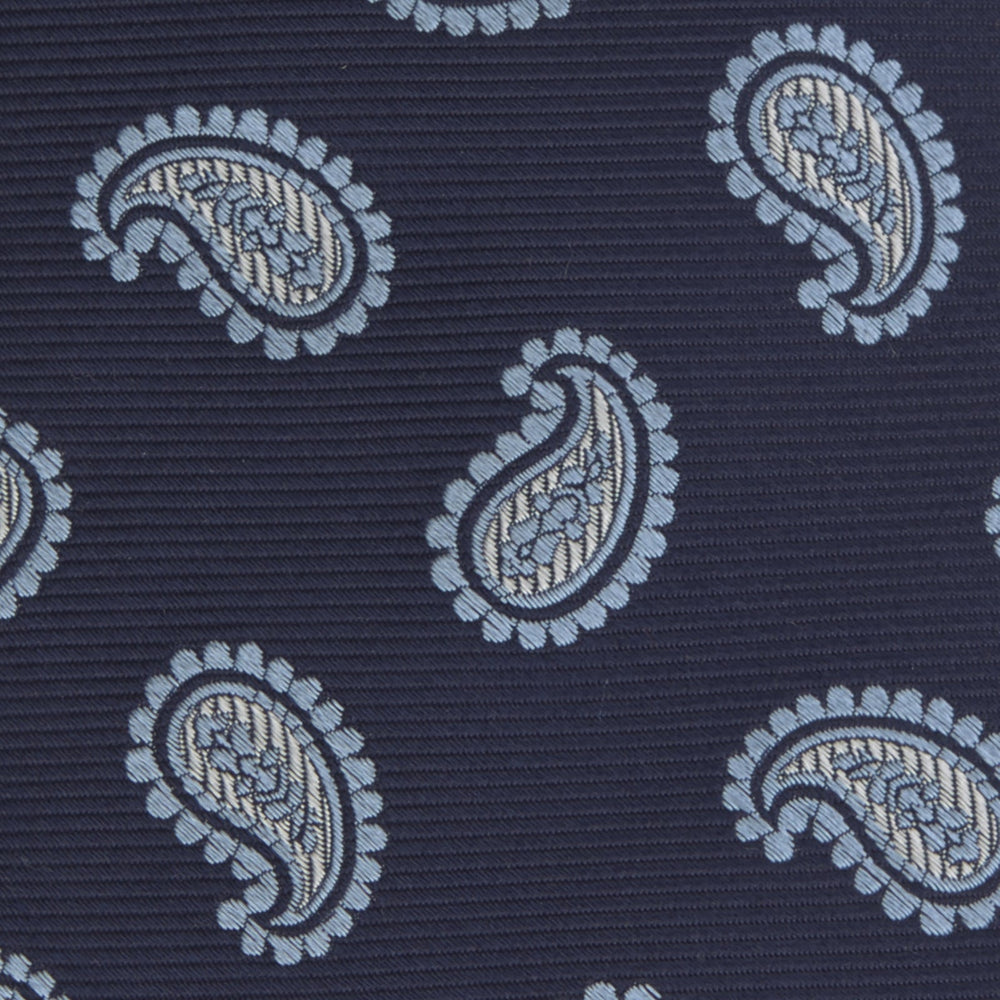 The Turnbull & Asser Navy and Light Blue Floating Paisley Silk Tie features a repeating light blue and white paisley pattern set against a navy blue silk backdrop.