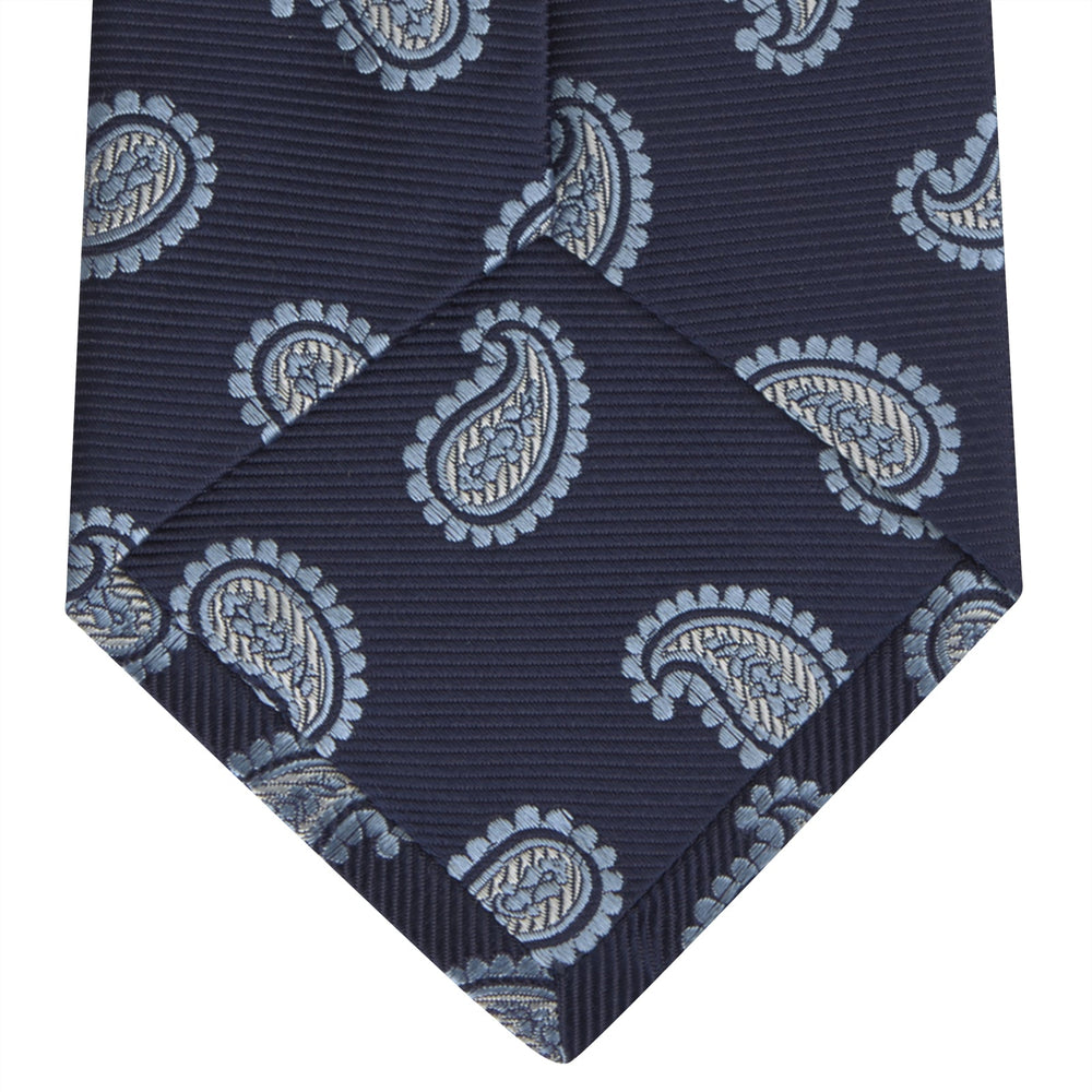 The Turnbull & Asser Navy and Light Blue Floating Paisley Silk Tie features a repeating light blue and white paisley pattern set against a navy blue silk backdrop.