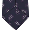 View 4 of product The Turnbull & Asser Navy and Plum Floating Paisley Silk Tie features a repeating purple and white paisley pattern, elegantly rolled up on a white background.