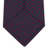 View 4 of product The Turnbull & Asser Navy and Red Paint Spot Silk Tie, featuring red spots on navy blue silk, is rolled with the wide end forward—ideal for office shirts and shown against a white background.