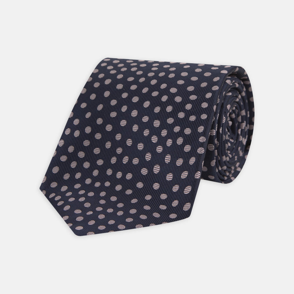 The Turnbull & Asser Navy and Pink Paint Spot Silk Tie, rolled at one end and set against a white background, adds a stylish touch to any office shirt with its modern spot pattern.