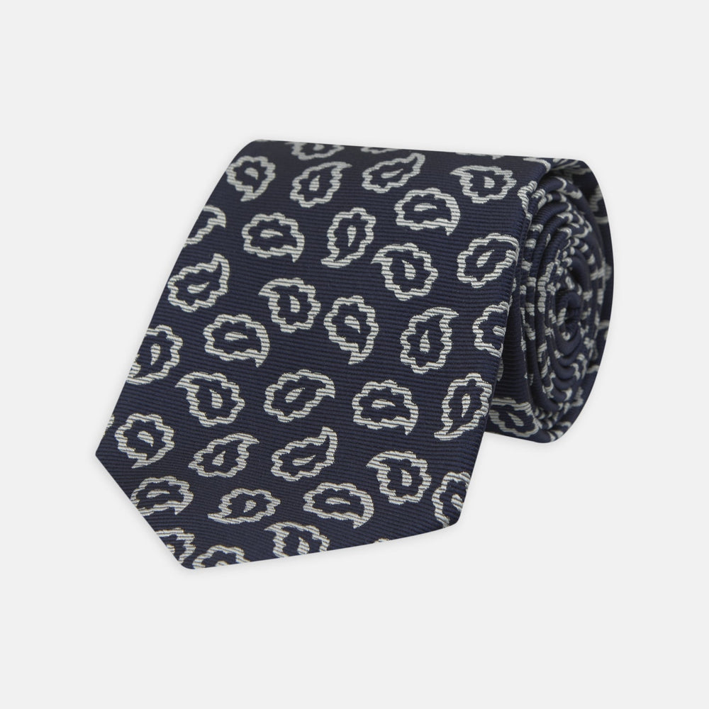 The Turnbull & Asser Navy and White Petal Paisley Silk Tie, featuring an elegant abstract pattern, is neatly rolled against a plain white background.