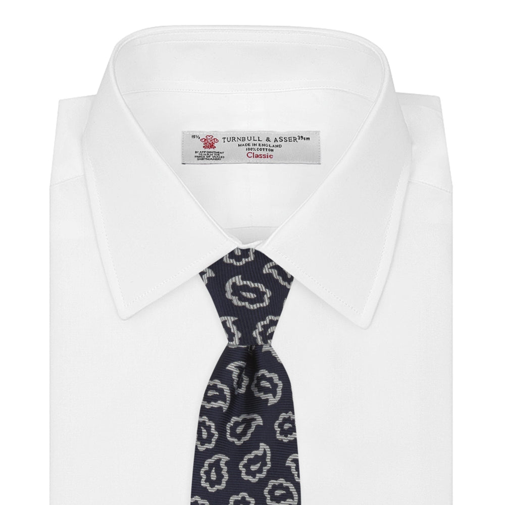 The Turnbull & Asser Navy and White Petal Paisley Silk Tie, featuring an elegant abstract pattern, is neatly rolled against a plain white background.
