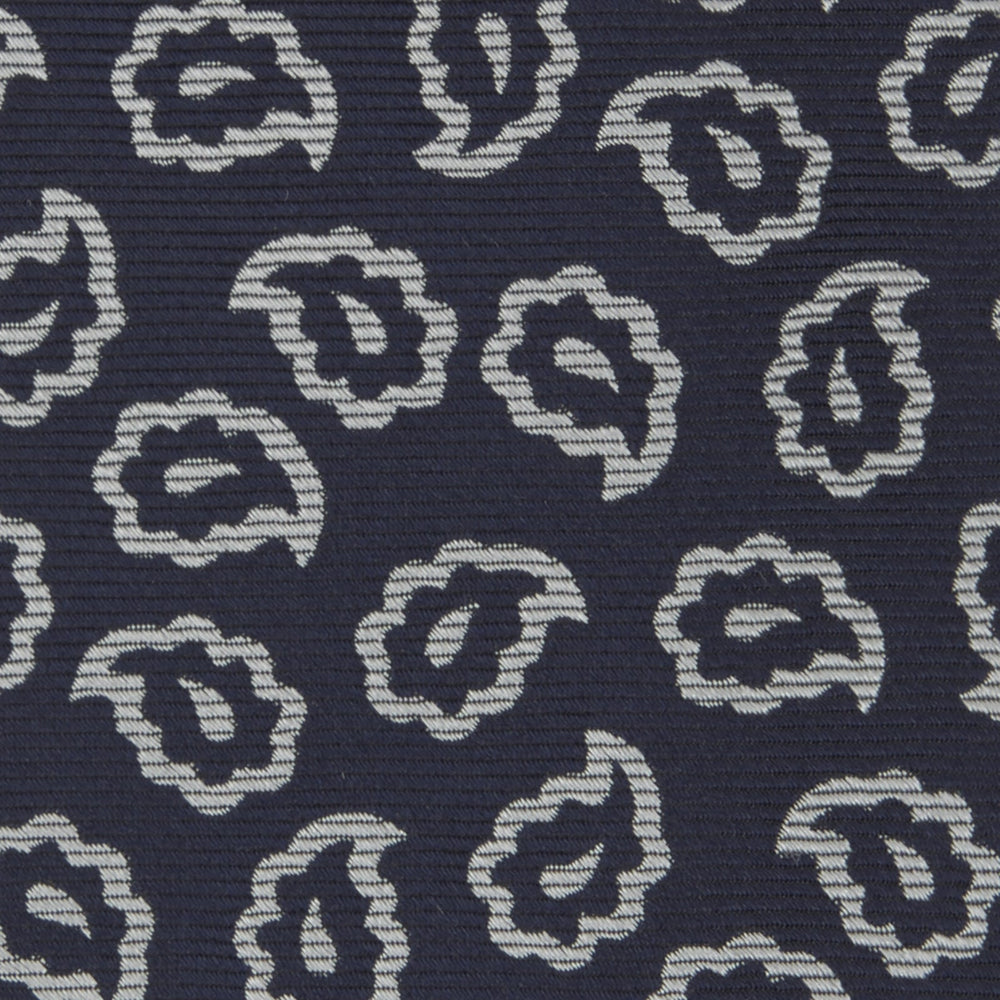 The Turnbull & Asser Navy and White Petal Paisley Silk Tie, featuring an elegant abstract pattern, is neatly rolled against a plain white background.
