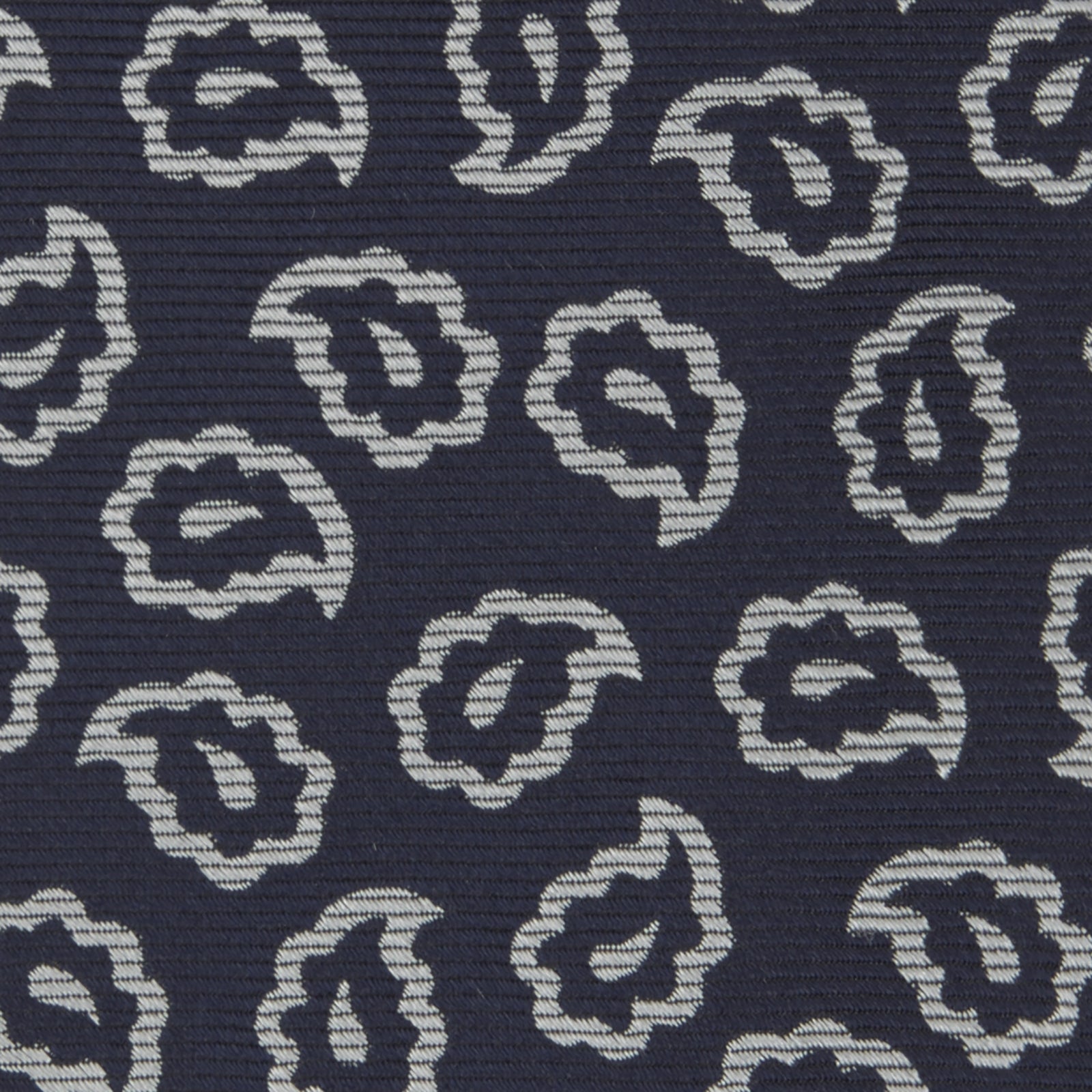 View 3 of product The Turnbull & Asser Navy and White Petal Paisley Silk Tie, featuring an elegant abstract pattern, is neatly rolled against a plain white background.