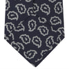 View 4 of product The Turnbull & Asser Navy and White Petal Paisley Silk Tie, featuring an elegant abstract pattern, is neatly rolled against a plain white background.