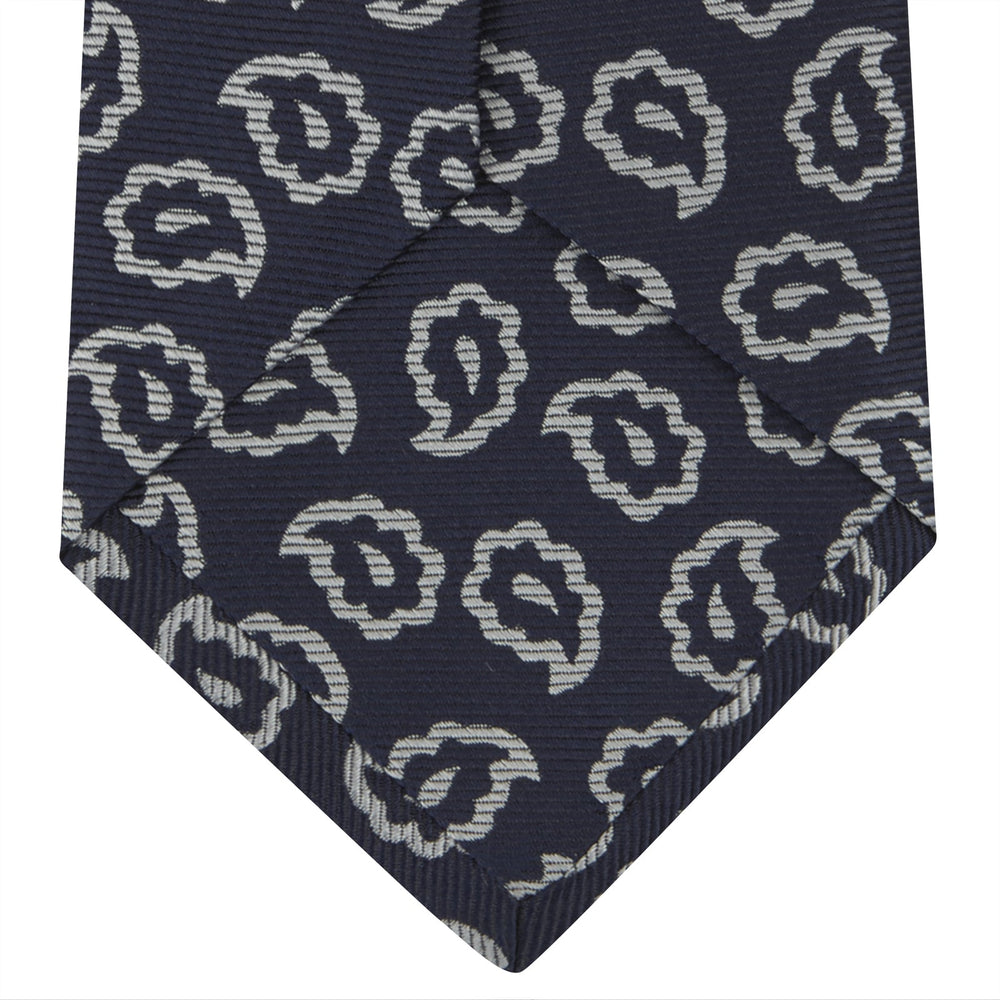The Turnbull & Asser Navy and White Petal Paisley Silk Tie, featuring an elegant abstract pattern, is neatly rolled against a plain white background.