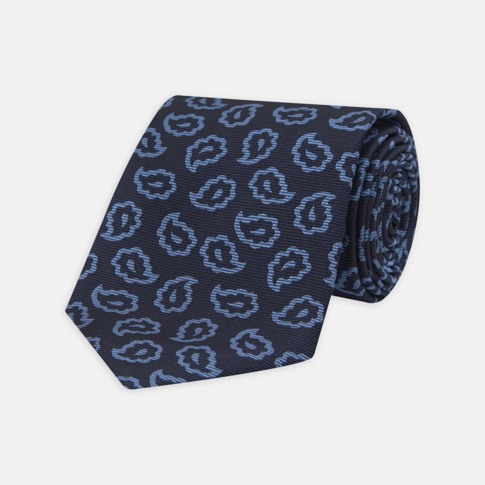 The Navy and Blue Petal Paisley Silk Tie by Turnbull & Asser features an abstract pattern of light blue paisley-like shapes, rolled up and displayed on a white background.