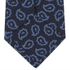 View 4 of product The Navy and Blue Petal Paisley Silk Tie by Turnbull & Asser features an abstract pattern of light blue paisley-like shapes, rolled up and displayed on a white background.