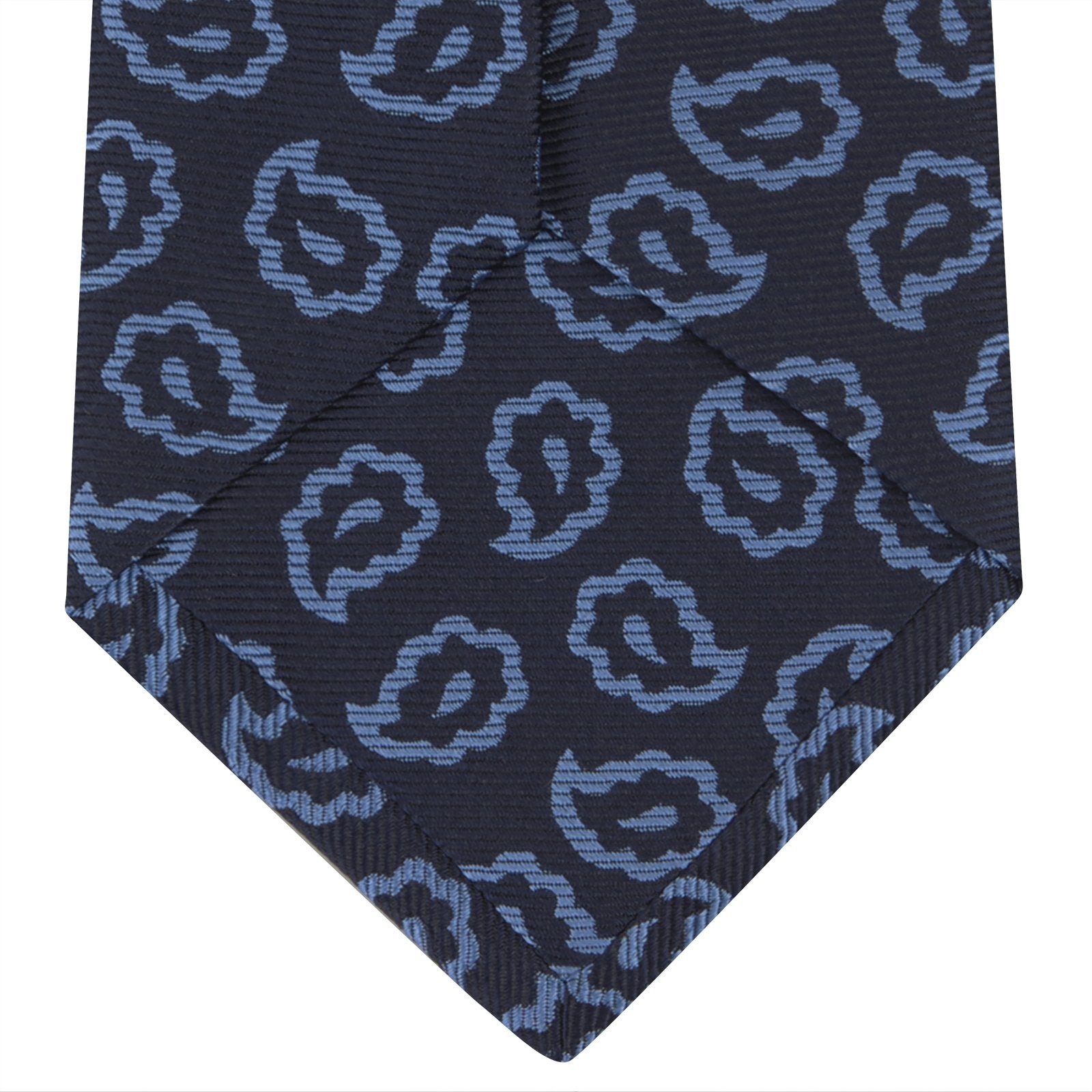 View 4 of product The Navy and Blue Petal Paisley Silk Tie by Turnbull & Asser features an abstract pattern of light blue paisley-like shapes, rolled up and displayed on a white background.