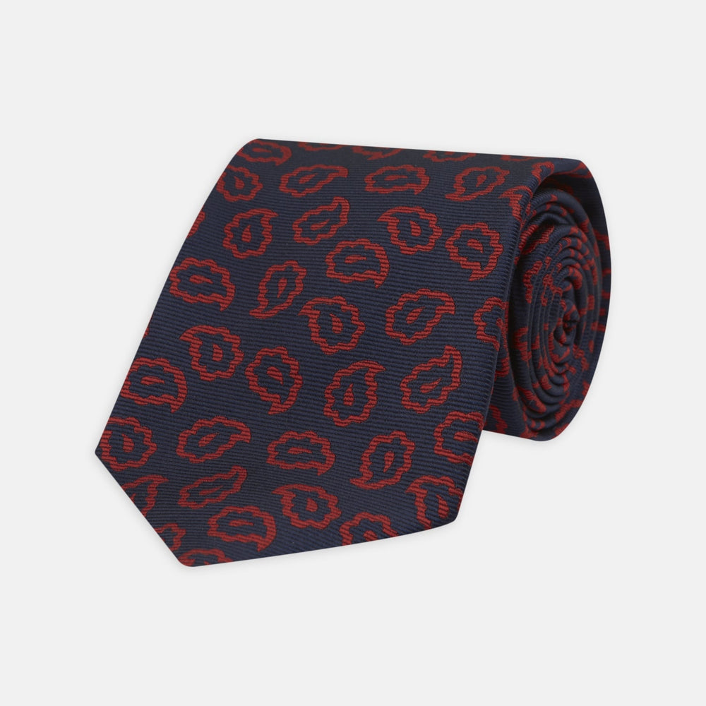 The Navy and Red Petal Paisley Silk Tie by Turnbull & Asser features an elegant paisley pattern on navy silk, rolled at one end and displayed on a plain white background.