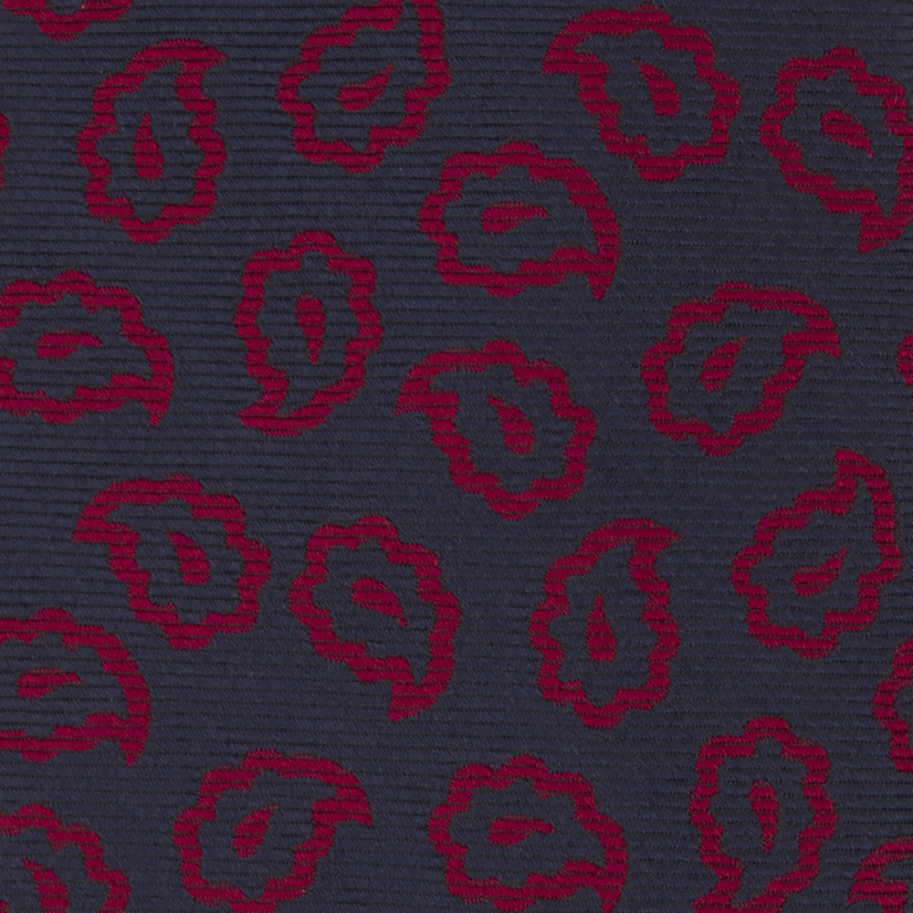 The Navy and Red Petal Paisley Silk Tie by Turnbull & Asser features an elegant paisley pattern on navy silk, rolled at one end and displayed on a plain white background.