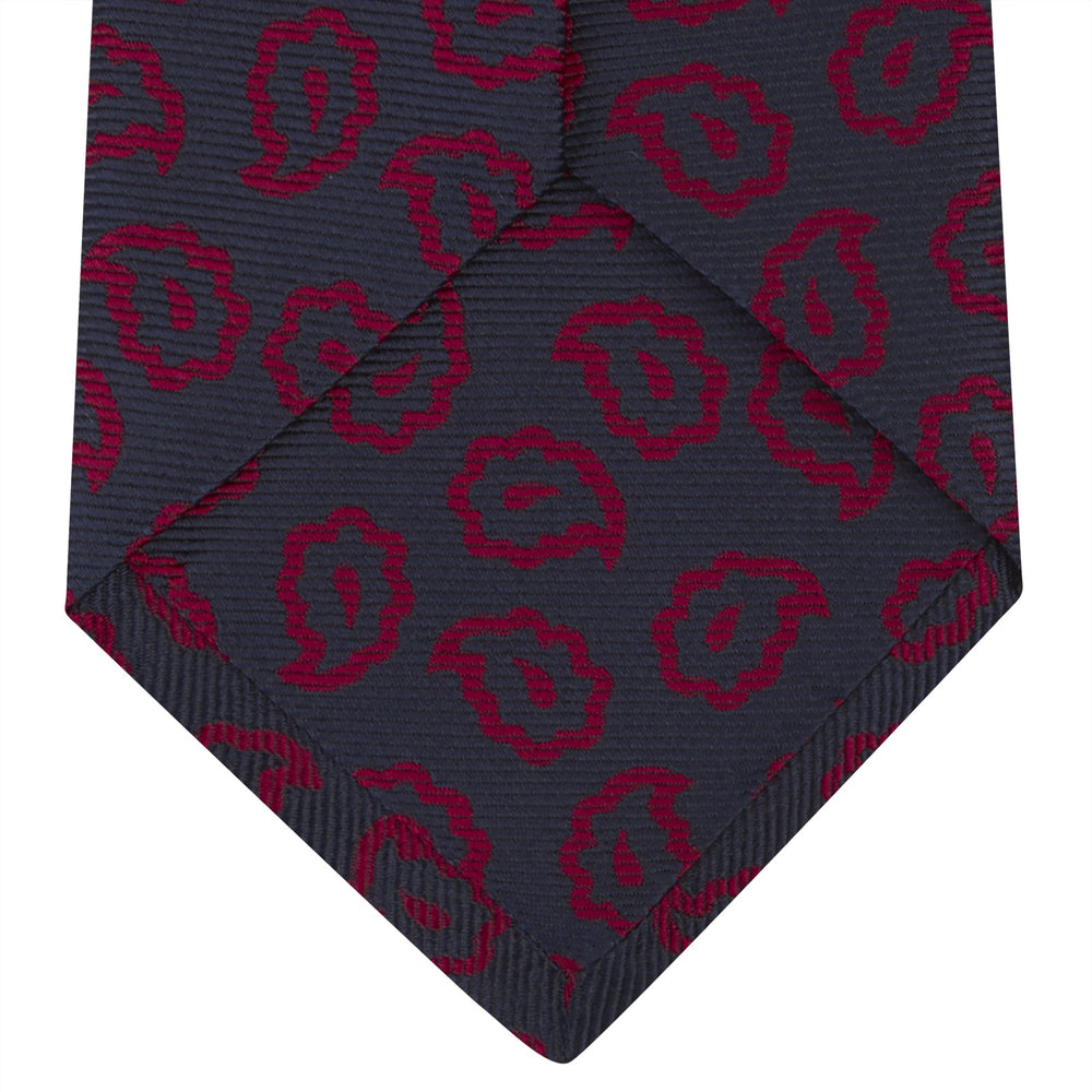 The Navy and Red Petal Paisley Silk Tie by Turnbull & Asser features an elegant paisley pattern on navy silk, rolled at one end and displayed on a plain white background.