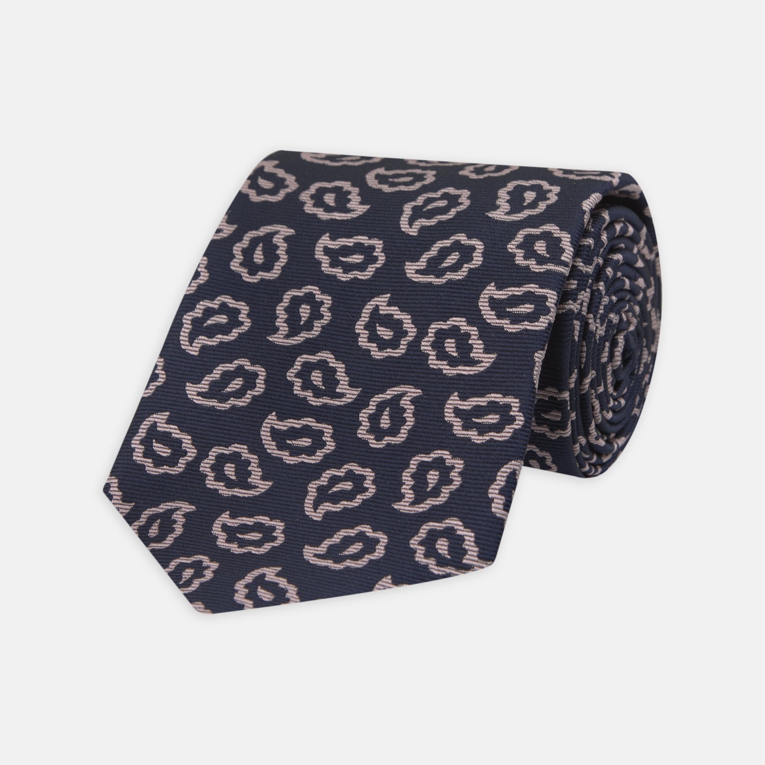View 1 of product The Turnbull & Asser Navy and Pink Petal Paisley Silk Tie features a repeating petal paisley pattern in pink, shown rolled with the pointed end forward against a plain white background.