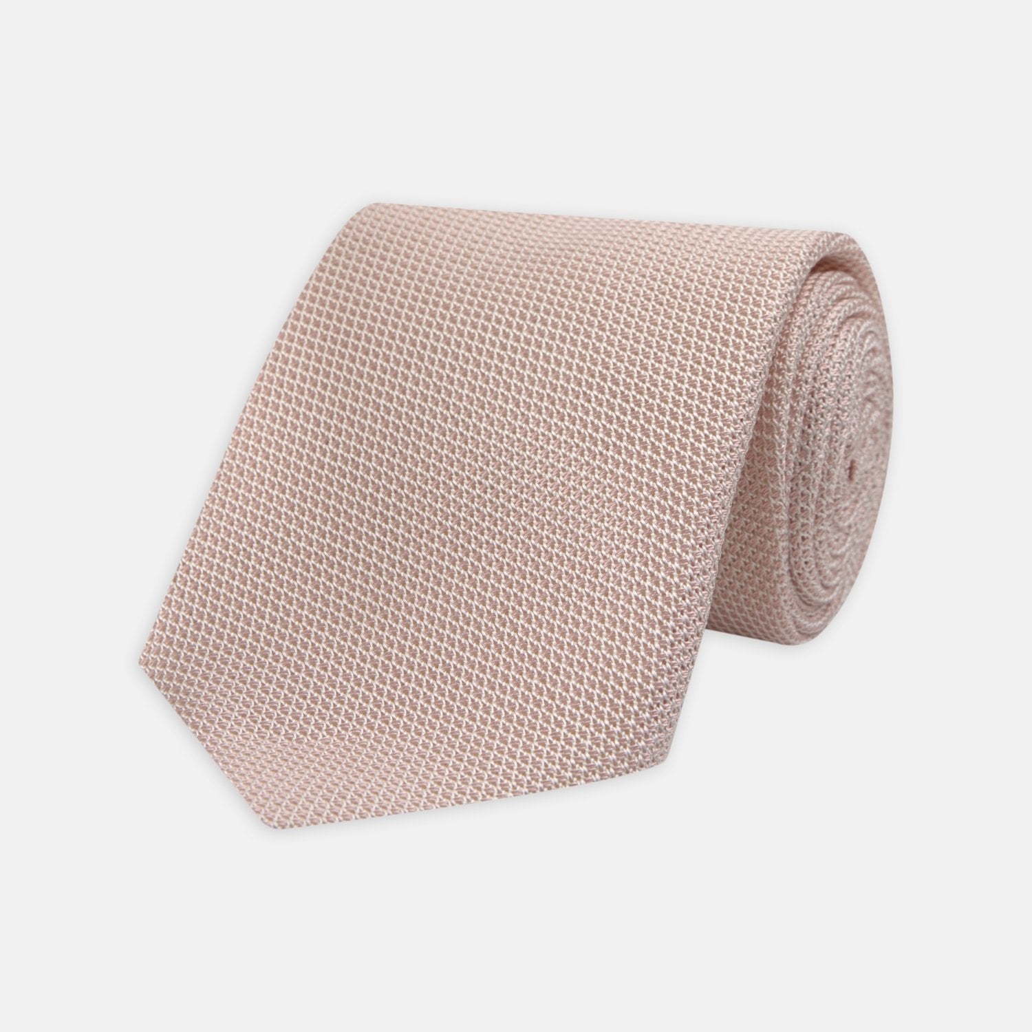 View 1 of product The Turnbull & Asser Light Pink Grenadine Silk Tie features a subtle woven pattern, shown rolled up on a plain white background.