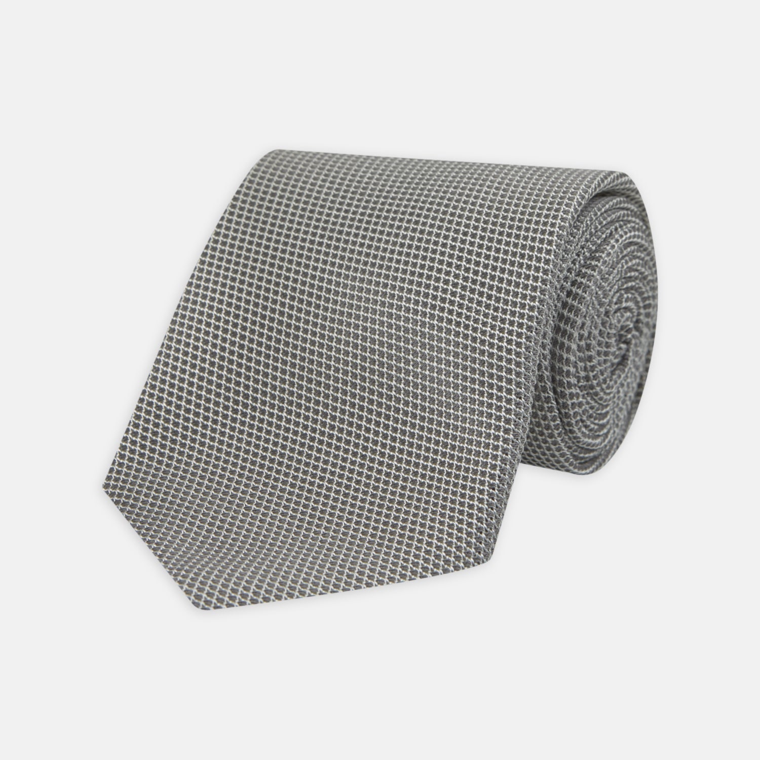 View 1 of product The Turnbull & Asser Light Grey Grenadine Silk Tie features a finely textured checkered pattern and superb dimensional stability, shown rolled up against a plain white background.