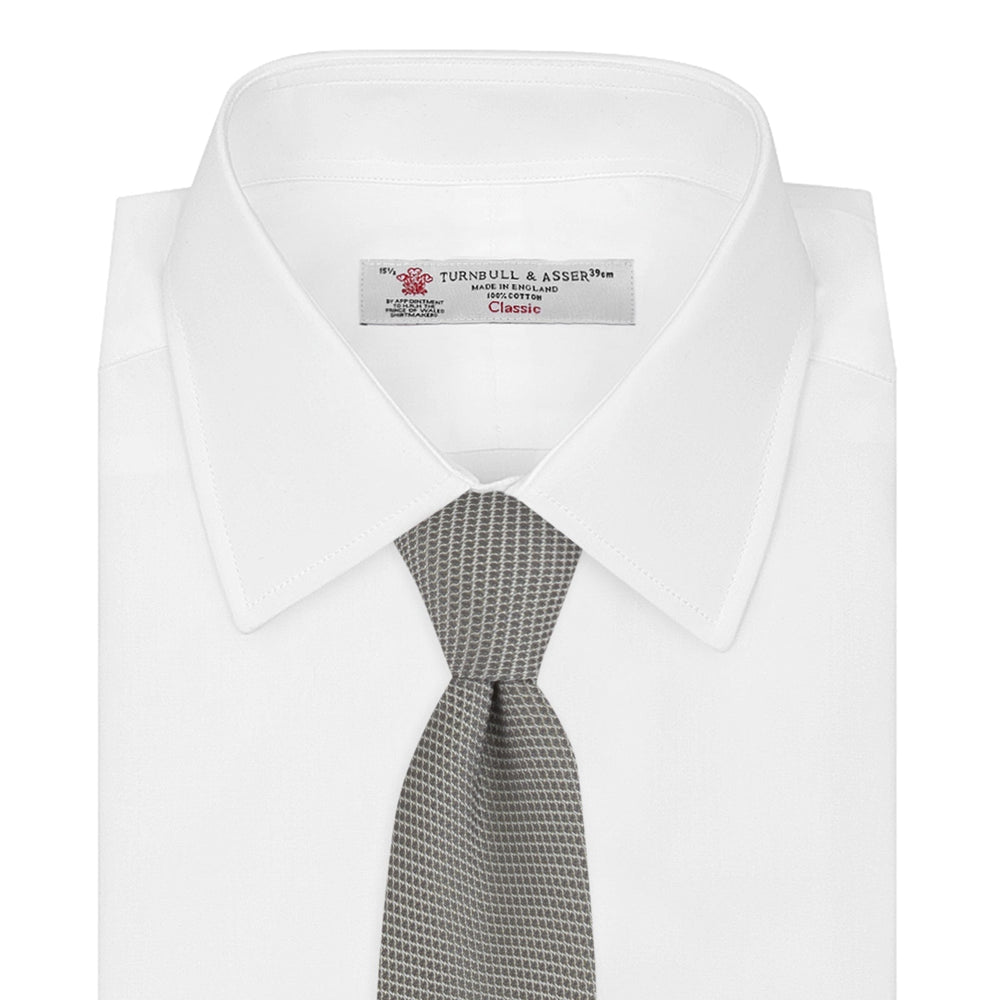 The Turnbull & Asser Light Grey Grenadine Silk Tie features a finely textured checkered pattern and superb dimensional stability, shown rolled up against a plain white background.