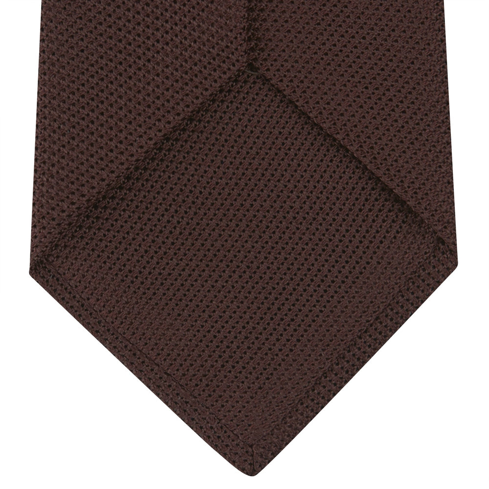 The Turnbull & Asser Burgundy Grenadine Silk Tie, featuring a textured grenadine weave, is rolled up and displayed against a plain white background.