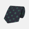 View 1 of product The Navy and Green Emblem Spot Silk Tie by Turnbull & Asser features a classic dark navy base with small green motif spots—perfect for adding a refined touch to your favorite office shirt.