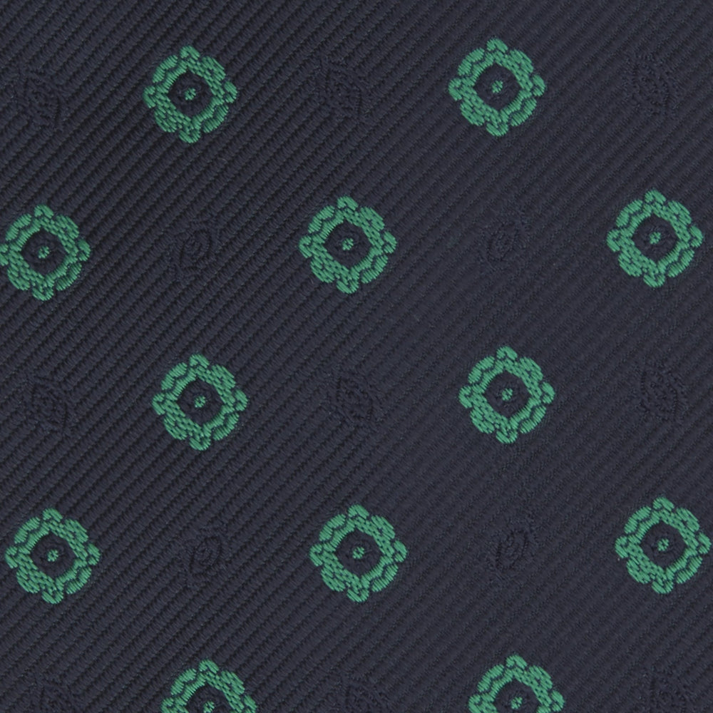 The Navy and Green Emblem Spot Silk Tie by Turnbull & Asser features a classic dark navy base with small green motif spots—perfect for adding a refined touch to your favorite office shirt.