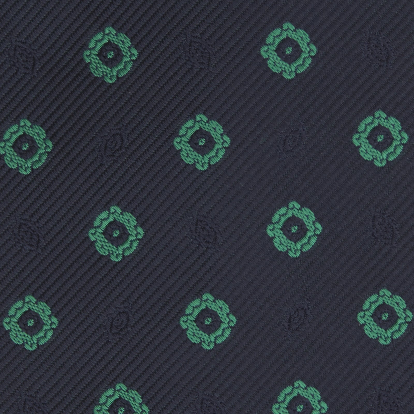 View 3 of product The Navy and Green Emblem Spot Silk Tie by Turnbull & Asser features a classic dark navy base with small green motif spots—perfect for adding a refined touch to your favorite office shirt.