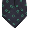 View 4 of product The Navy and Green Emblem Spot Silk Tie by Turnbull & Asser features a classic dark navy base with small green motif spots—perfect for adding a refined touch to your favorite office shirt.