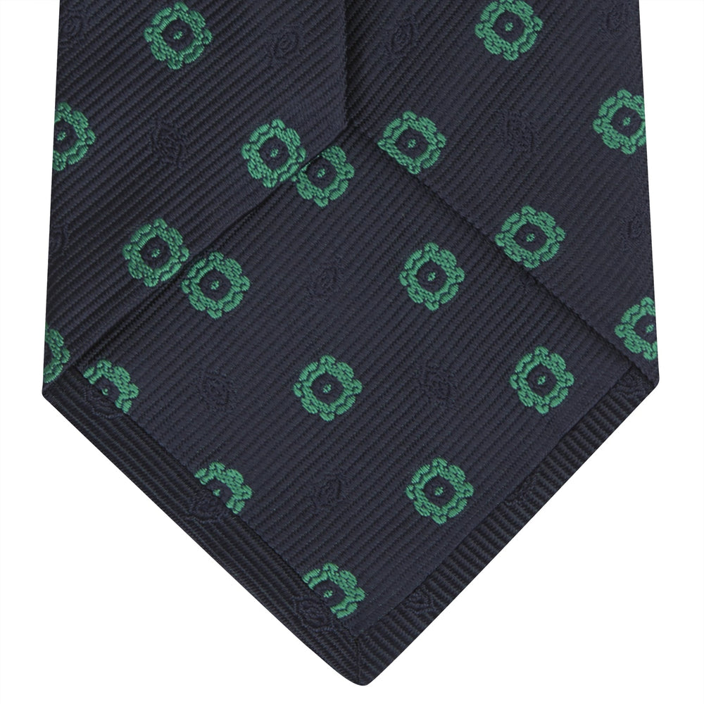 The Navy and Green Emblem Spot Silk Tie by Turnbull & Asser features a classic dark navy base with small green motif spots—perfect for adding a refined touch to your favorite office shirt.