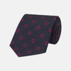 View 1 of product The Turnbull & Asser Navy and Dark Pink Emblem Spot Silk Tie features a classic pattern of small, evenly spaced emblems—ideal for complementing your favorite office shirt.