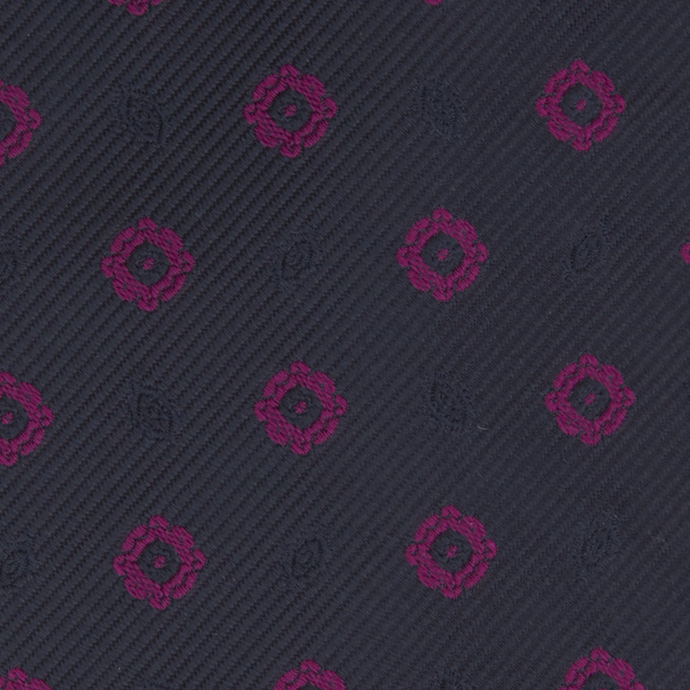The Turnbull & Asser Navy and Dark Pink Emblem Spot Silk Tie features a classic pattern of small, evenly spaced emblems—ideal for complementing your favorite office shirt.