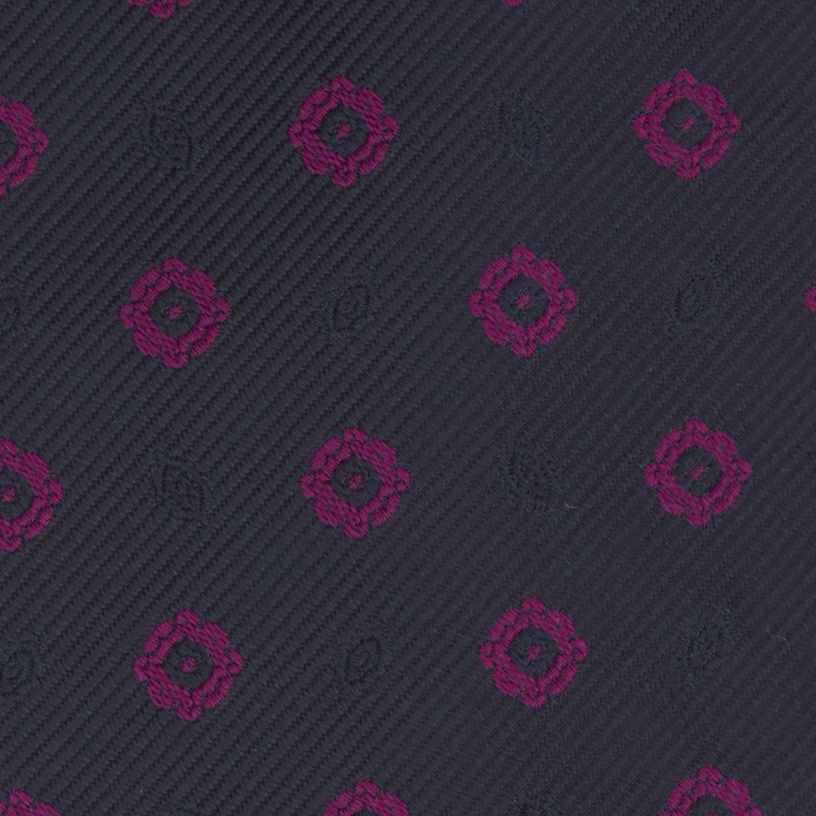 View 3 of product The Turnbull & Asser Navy and Dark Pink Emblem Spot Silk Tie features a classic pattern of small, evenly spaced emblems—ideal for complementing your favorite office shirt.
