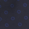 View 3 of product The Turnbull & Asser Navy and Blue Emblem Spot Silk Tie features a classic pattern of light blue motifs on navy silk, showcased rolled on a white background—a refined accessory for any office shirt.