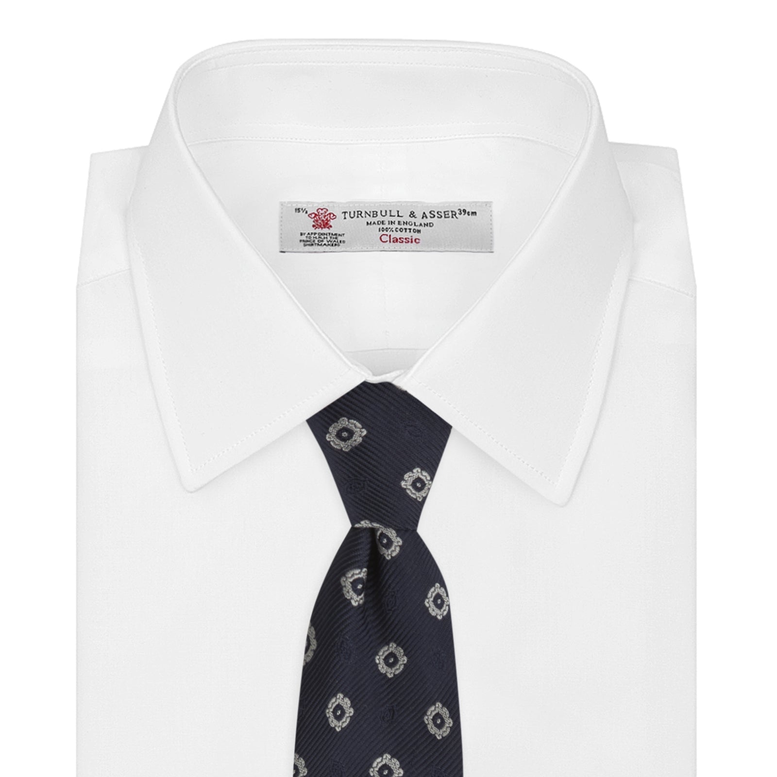 View 2 of product The Turnbull & Asser Navy and Silver Emblem Spot Silk Tie features a refined repeating emblem pattern in silver on navy silk, making it an elegant accessory for any office shirt.